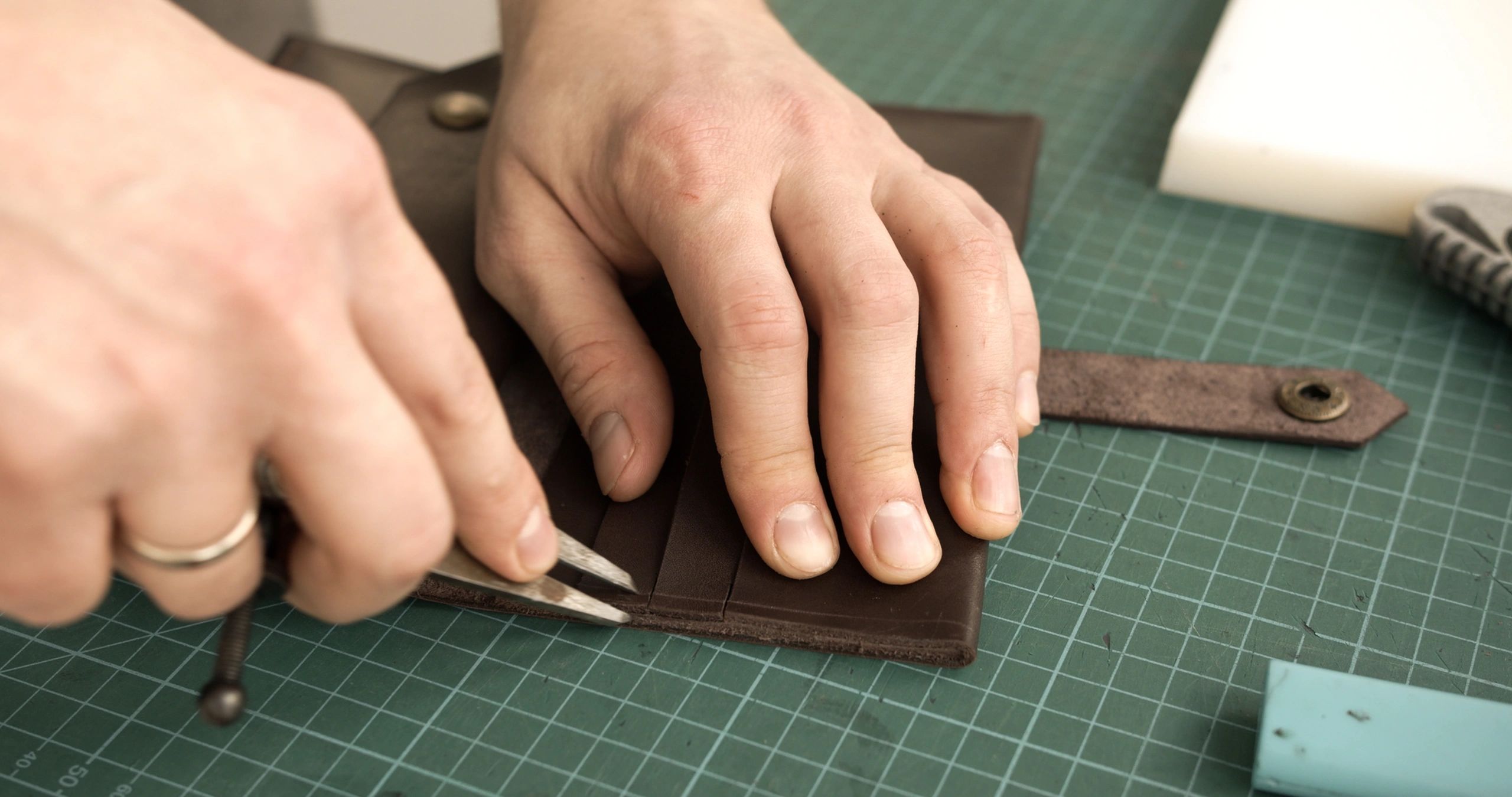 Craftsman hand-stitching a leather item with traditional tools
